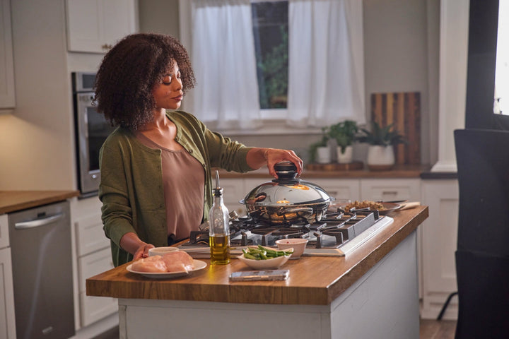 A by AMC covered pan on a stovetop with the Audiotherm clipped onto the Visiotherm lid knob.